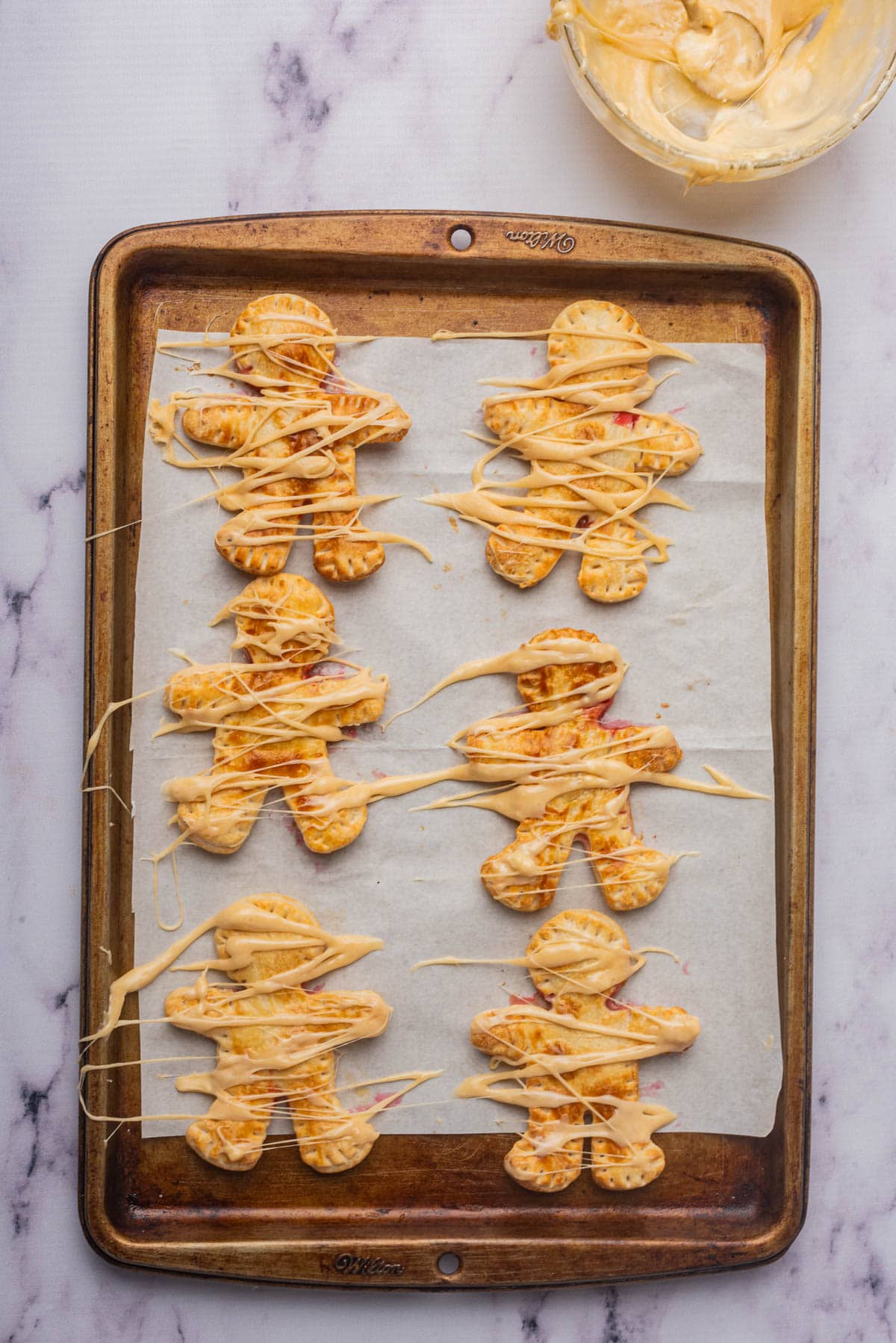 Marshmallow drizzled on person shaped hand pies.