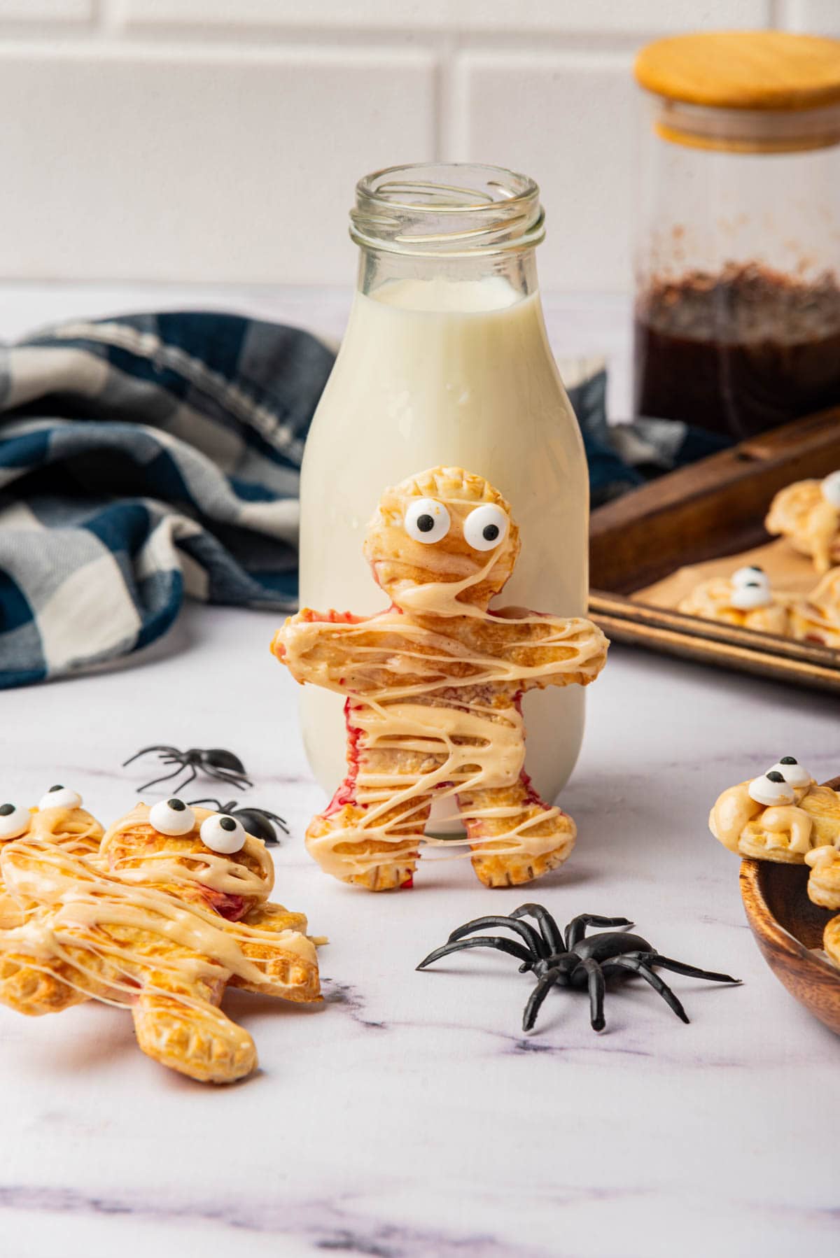 Mummy shaped individual pies with icing drizzle with bottle of milk and spider.