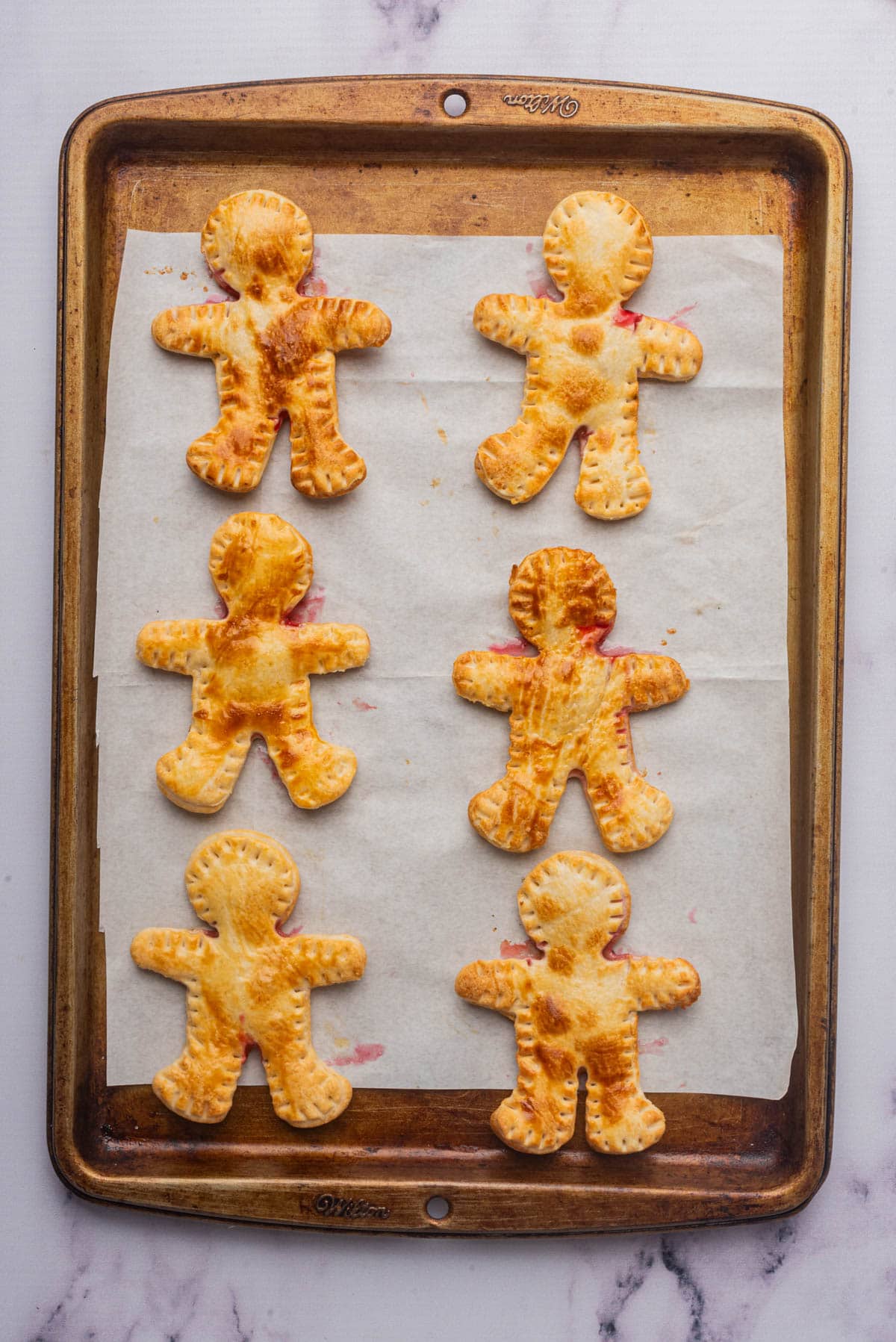 Baked gingerman shaped pies on baking sheet.