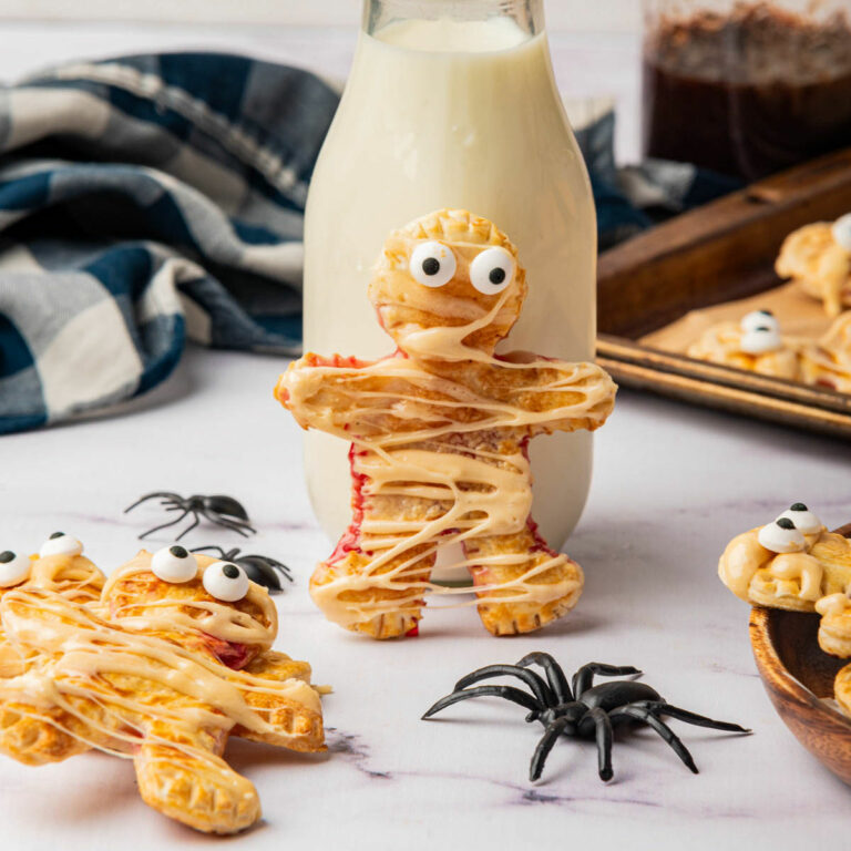 Mummy shaped individual pies with icing drizzle with bottle of milk and spider.