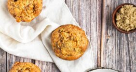 Peach muffin on wood table with another muffin in background.