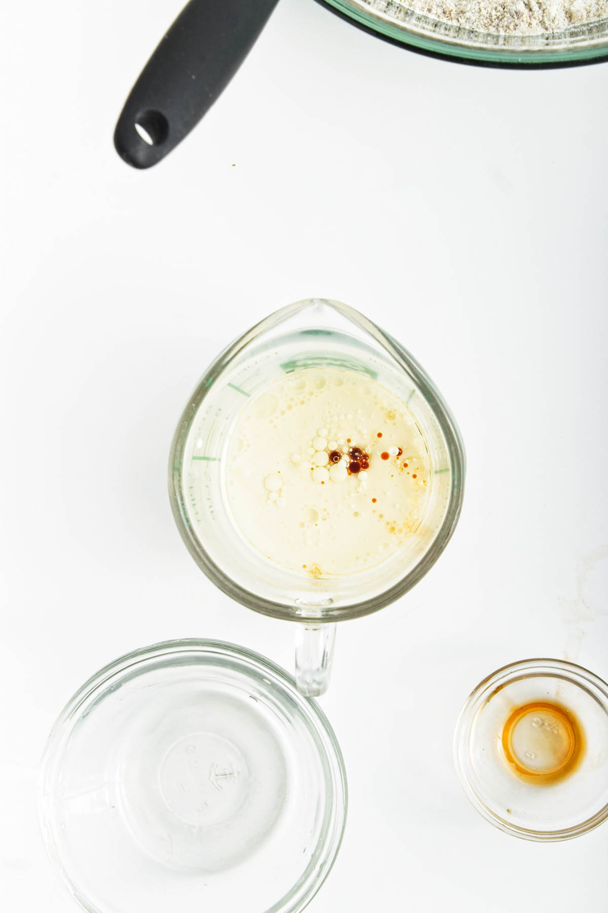 Almond milk, vanilla, and oil in glass measuring cup.