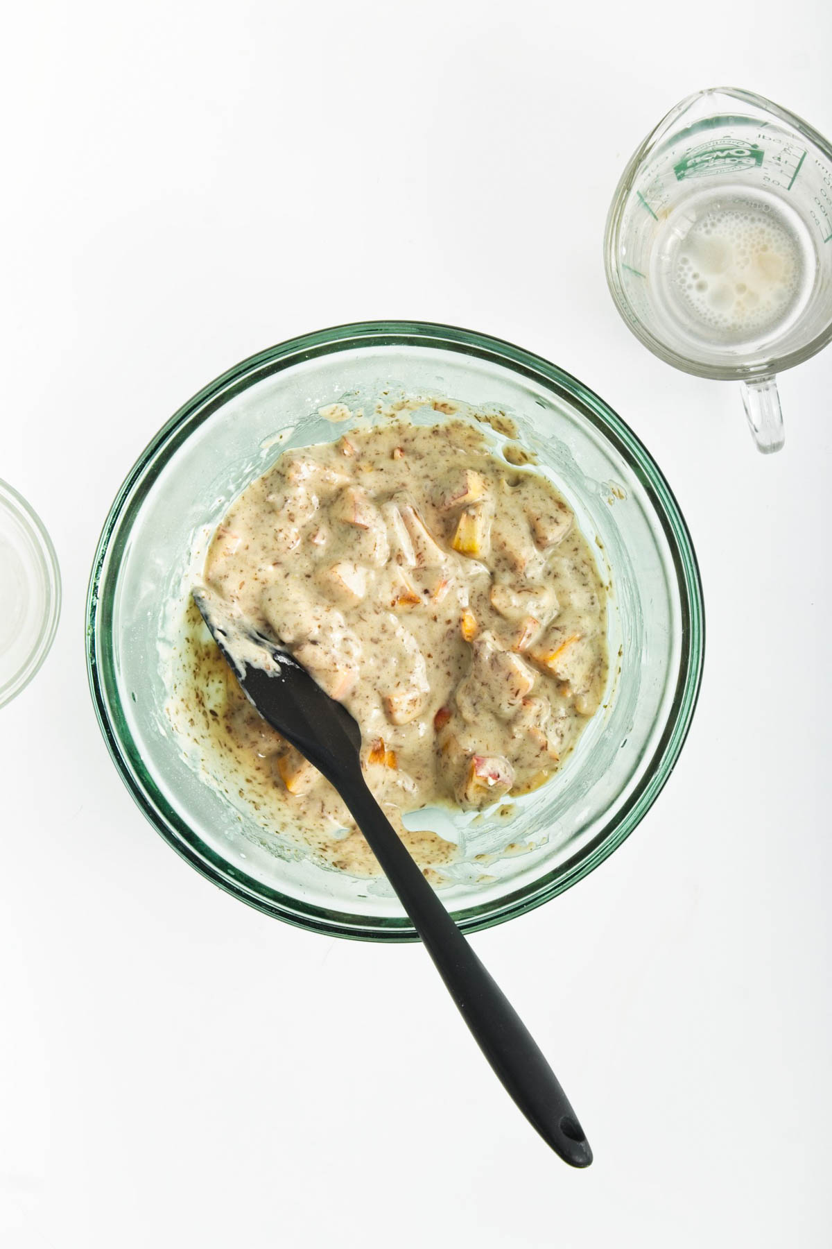 Muffin batter in glass bowl with measuring cup to the side.