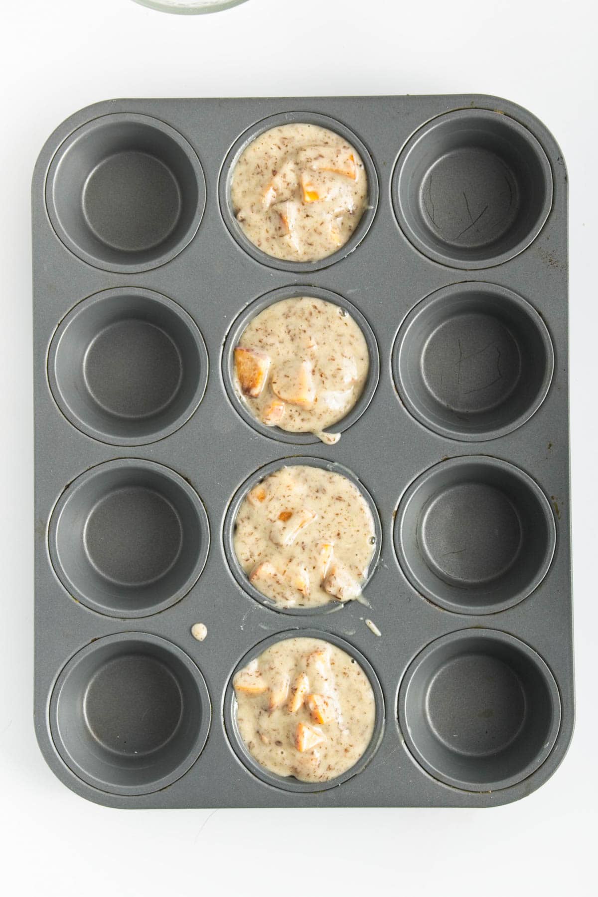 Four unbaked muffins in 12 hole muffin tin.