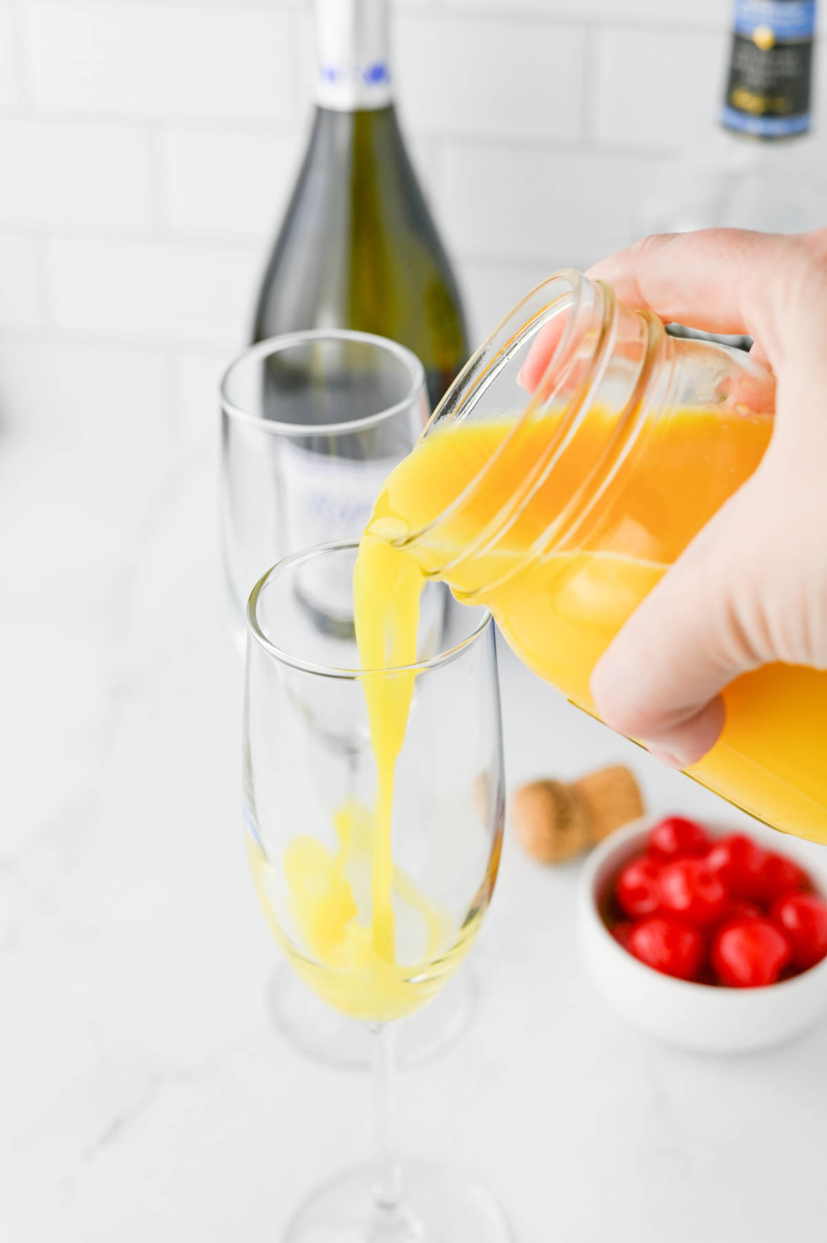 Pouring orange juice into champagne flute.