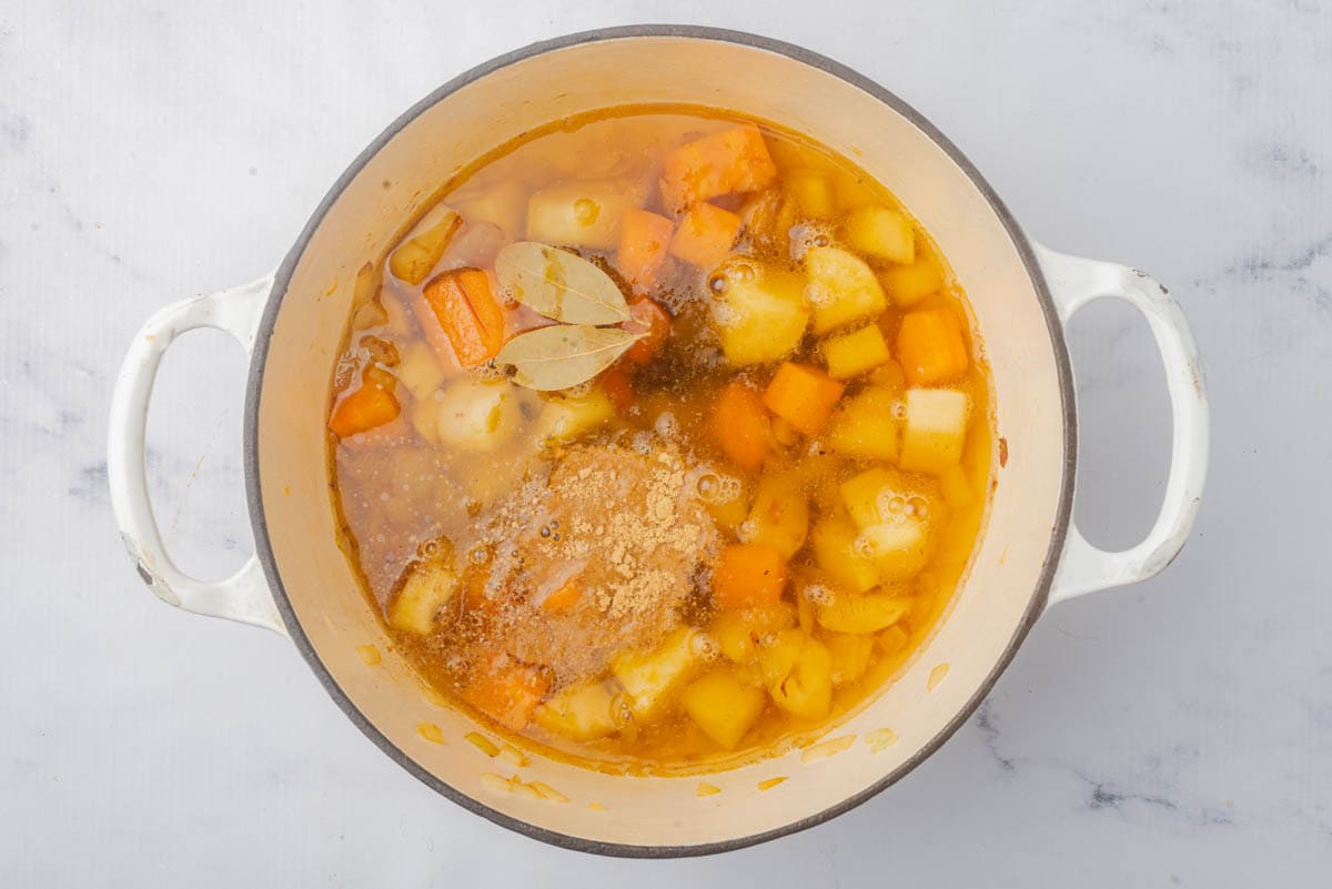 Carrots, onion, sweet potato, and butter in a pot with broth and spices.