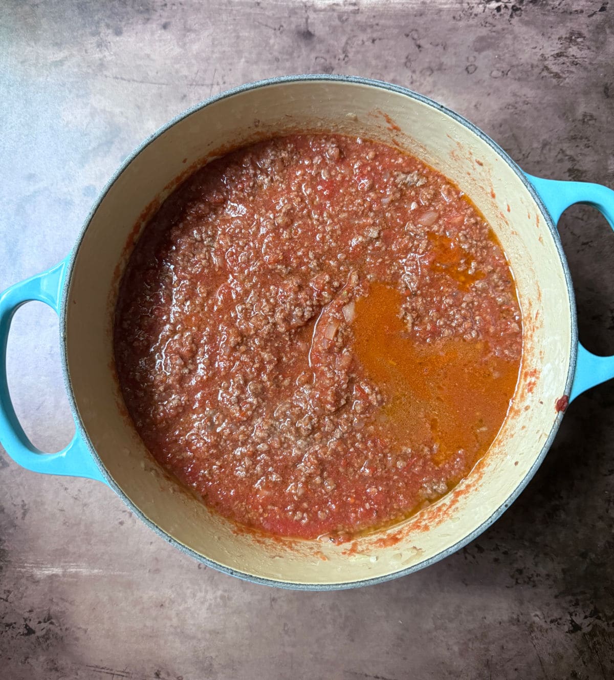 Ground beef with a tomato sauce in a blue pot.