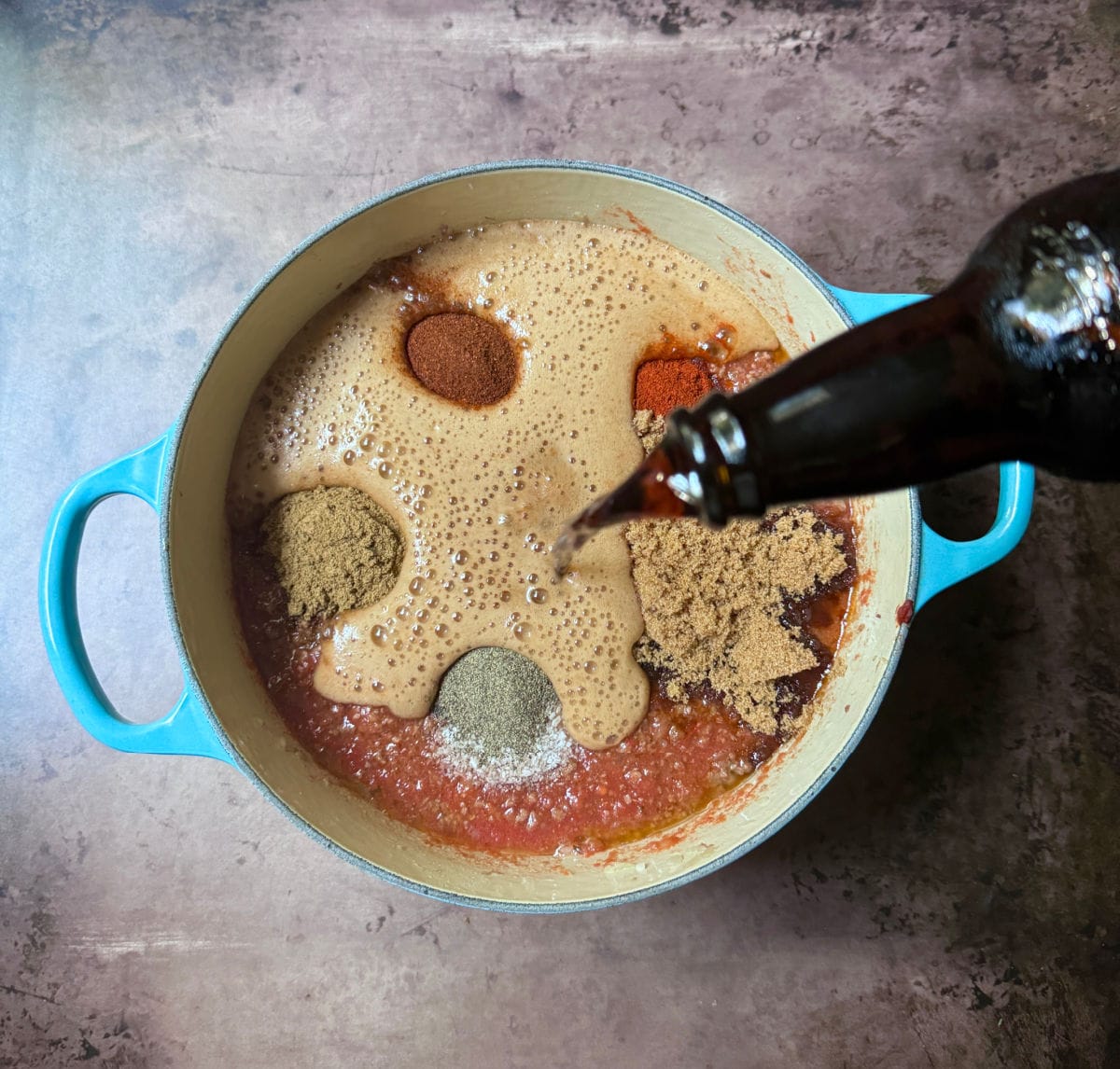 Pouring Guinness stout into a pot of chili.