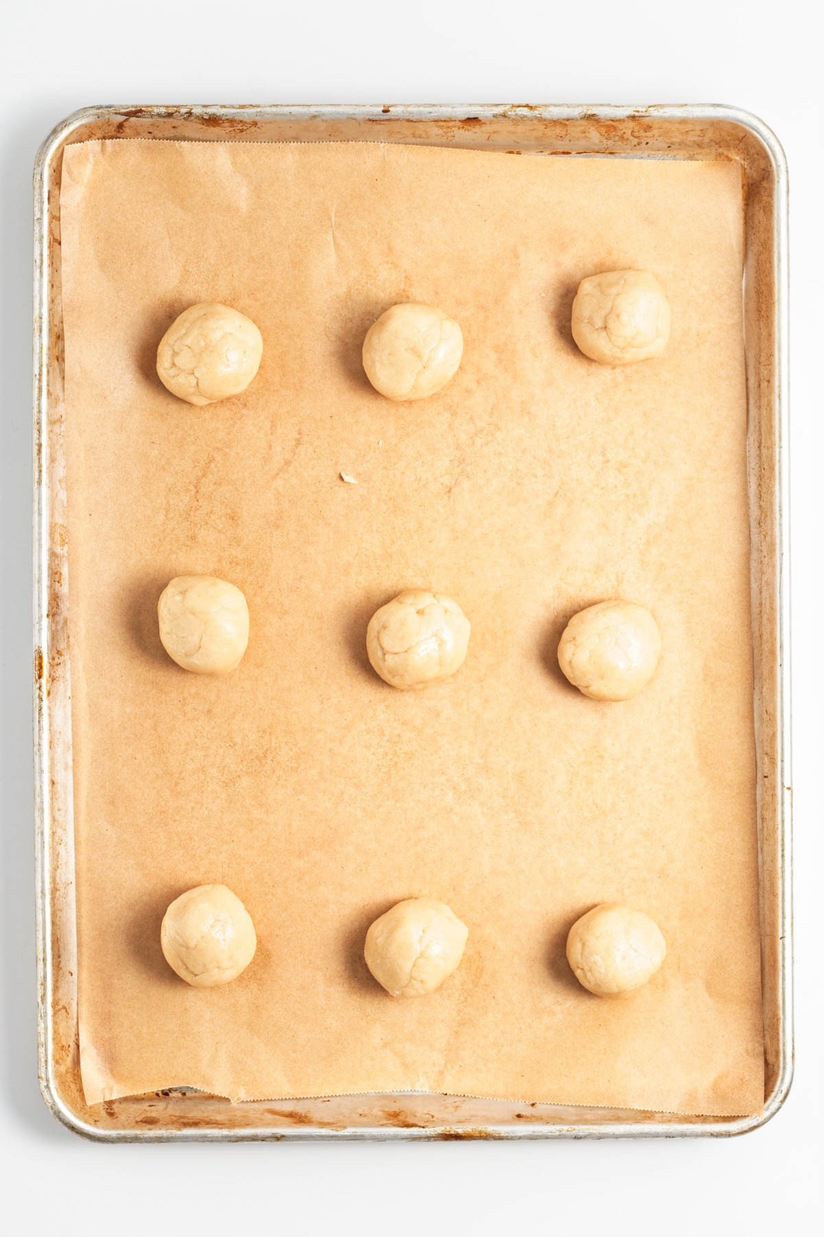 Cookie balls on parchment paper on cookie sheet.