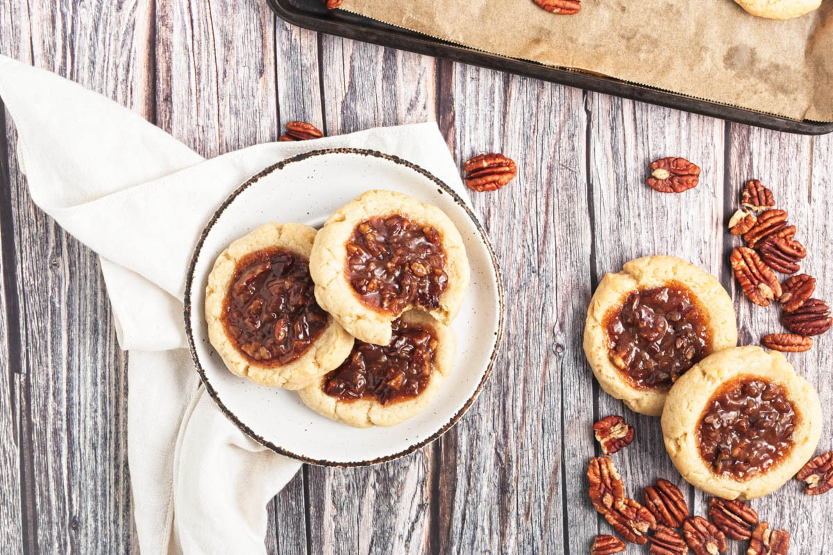 Pecan pie cookies on plate with more to the side on a wooden table.