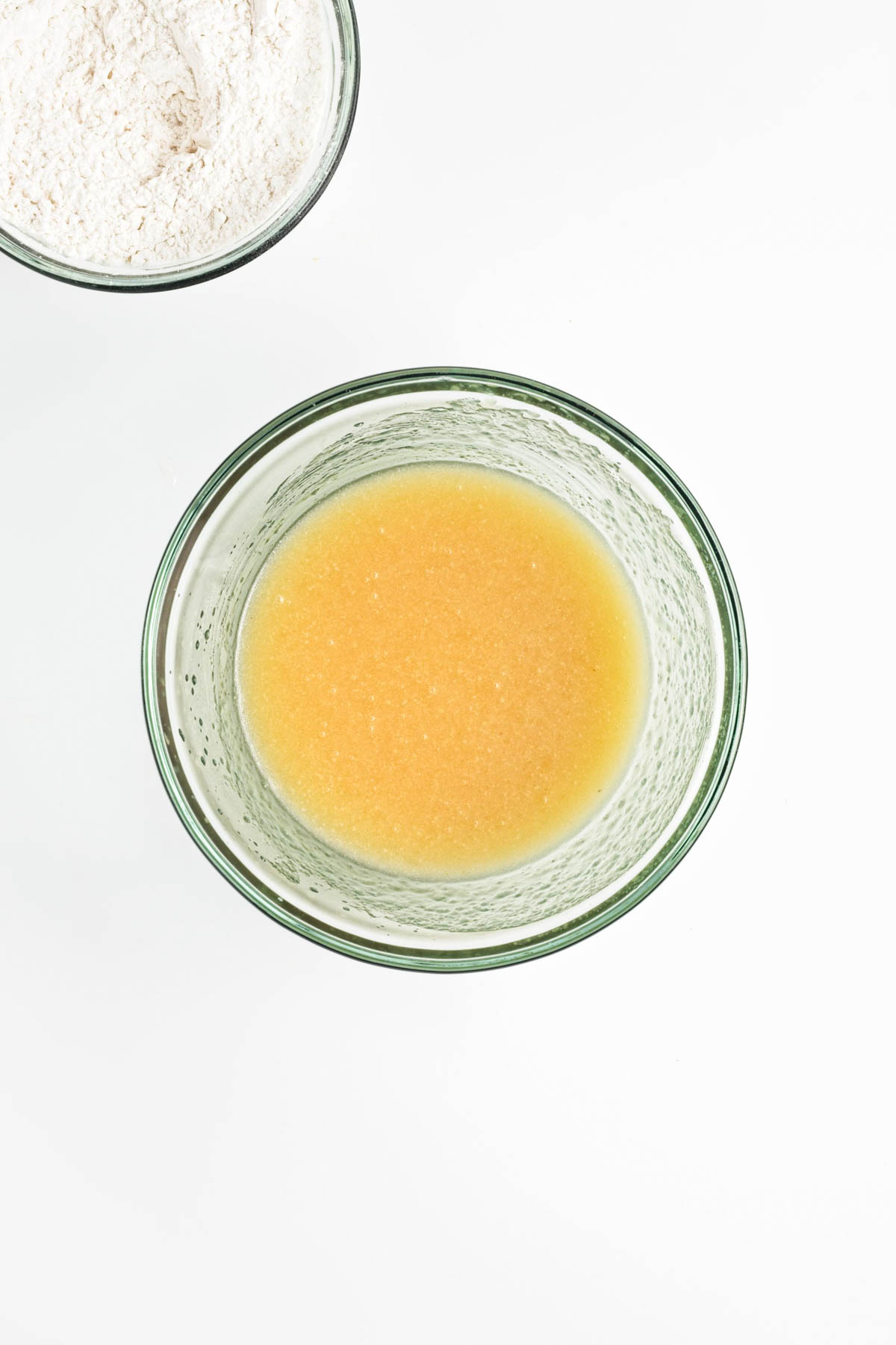 Oil, sugar, applesauce, and vanilla in a glass bowl mixed.