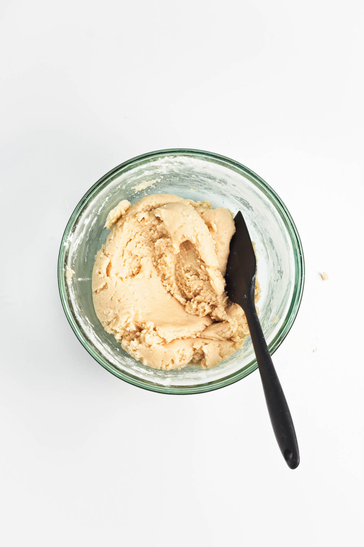 Cookie batter in a glass bowl with a spatula.