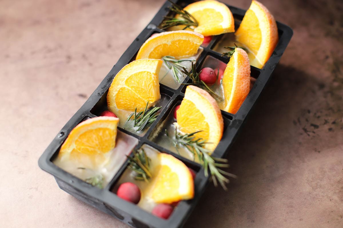 Ice cube tray filled with fruit on brown table.