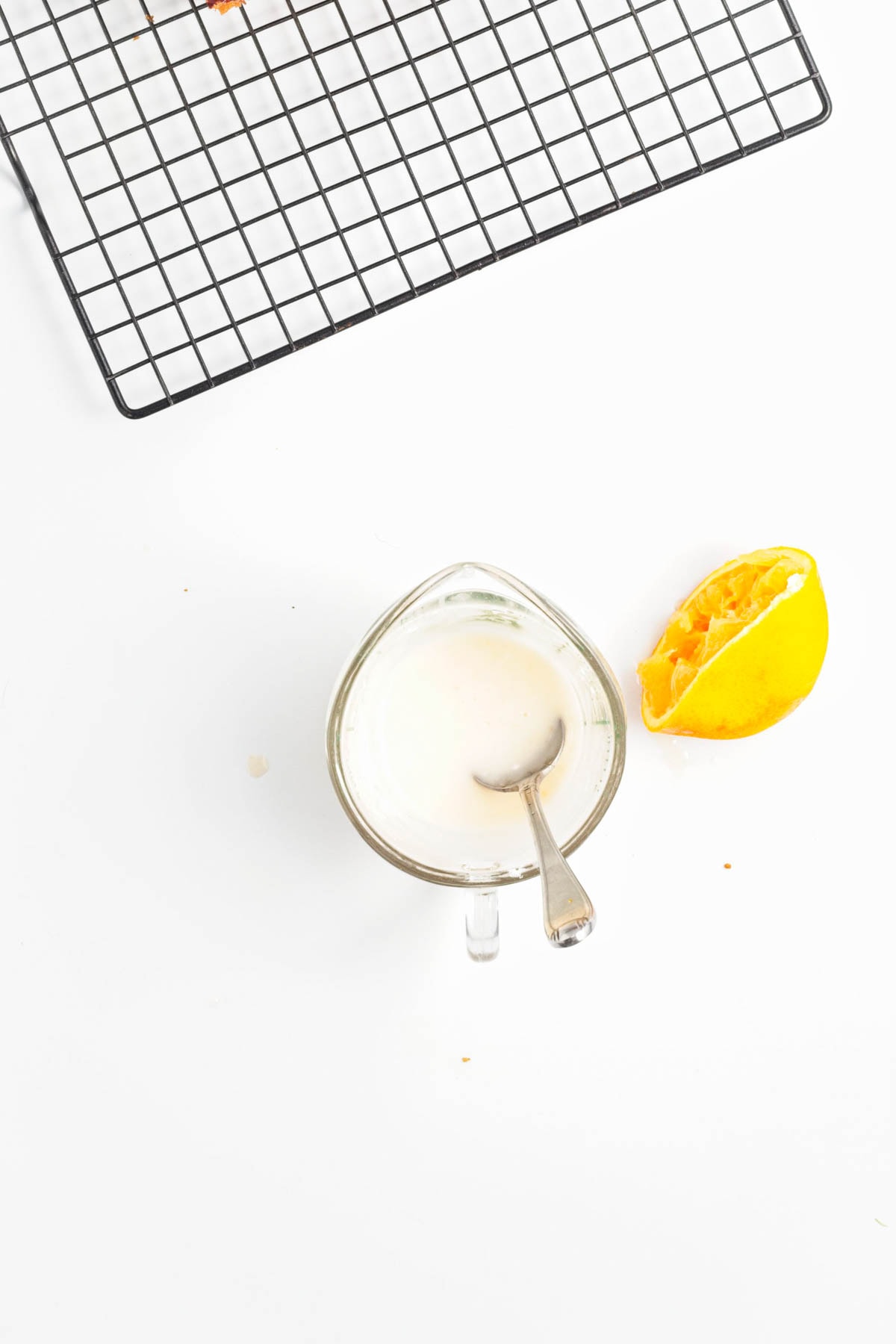 Rack above, mixing cup with icing and half of an orange already squeezed.