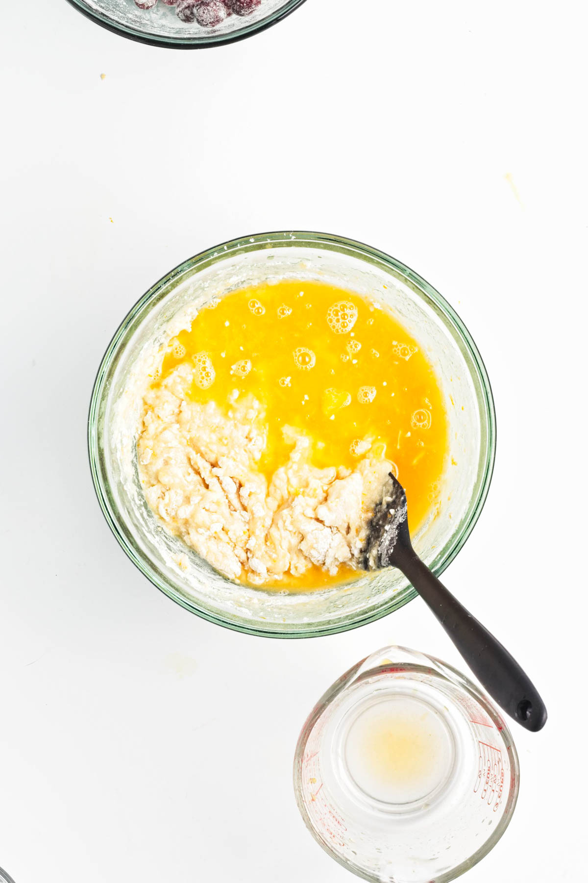 Batter to make bread in a glass bowl with black spatula.