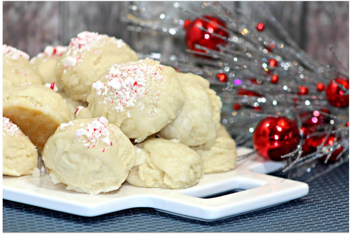 Cookies spinkled with candy canes on a white plate in front of Christmas decor.