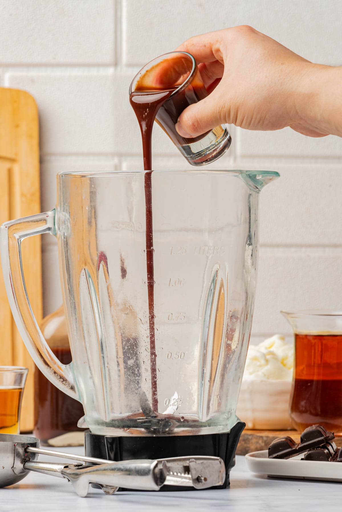 Adding dark creme de cacao to a blender.