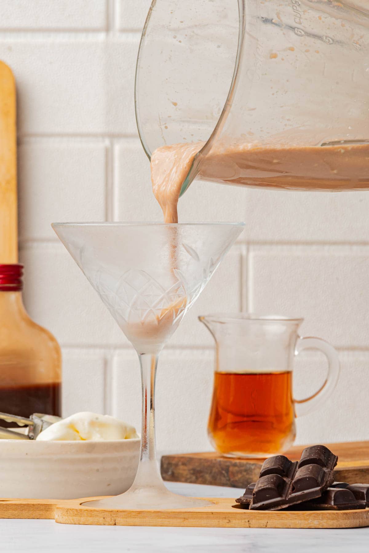 Pouring frozen chocolate drink into a tall cocktail glass.