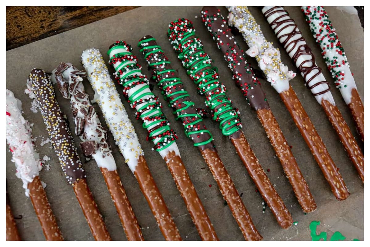 Chocolate covered pretzel rods on parchment paper.