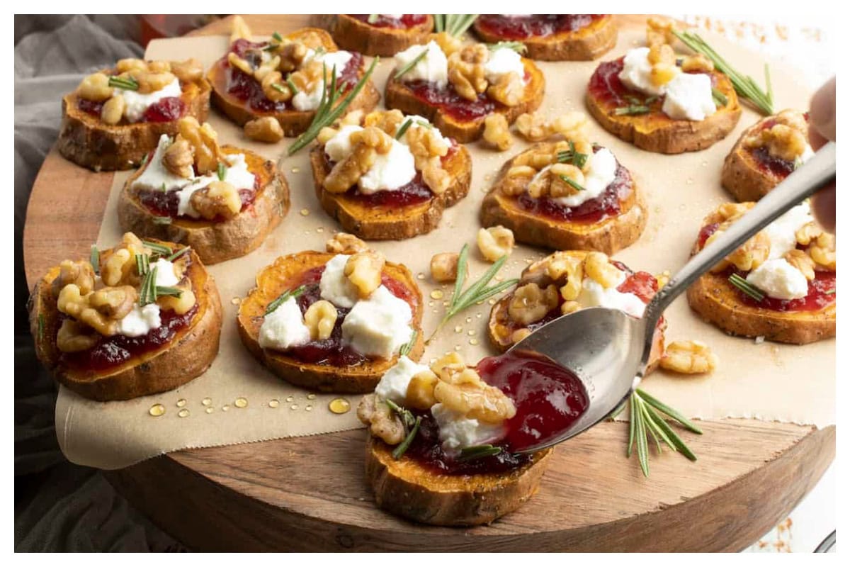 Sweet potato slices with cranberry sauce, cheese, nuts, and rosemary.