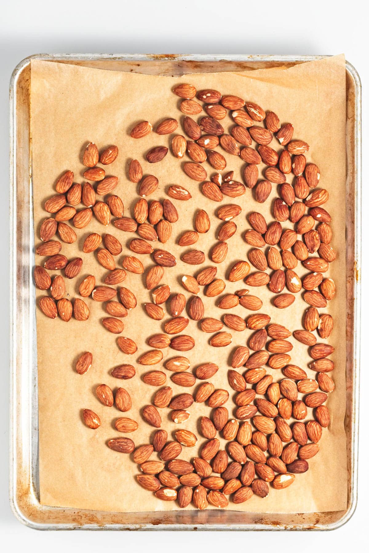 Almonds on parchment on a baking sheet.