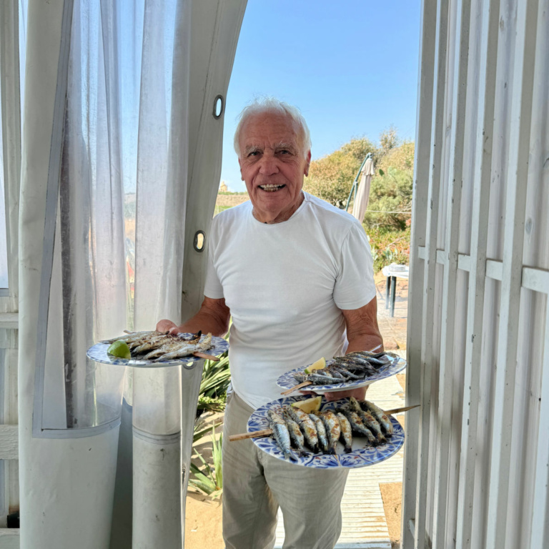 Man carrying plates of sardines.