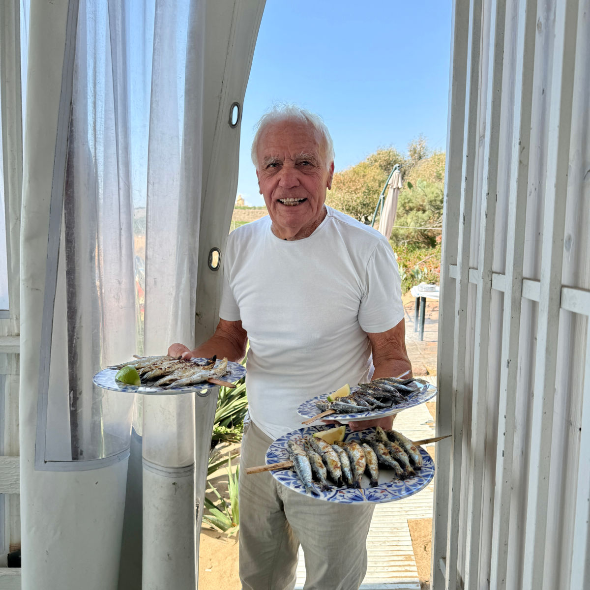 Man carrying plates of sardines.