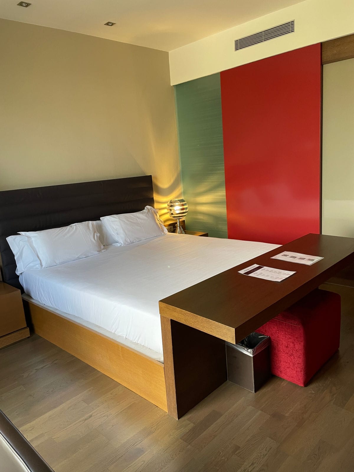 Bed with white sheets and wood headboard and footboard in a room painted yellow, green, and red.