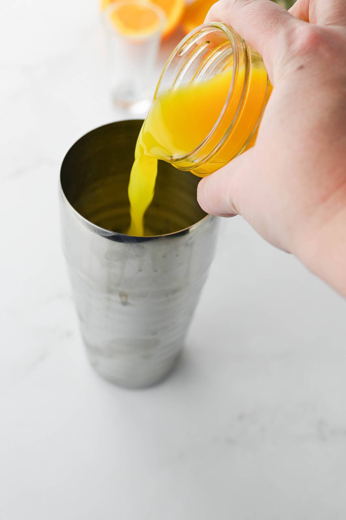 Pouring orange juice into a cocktail shaker.