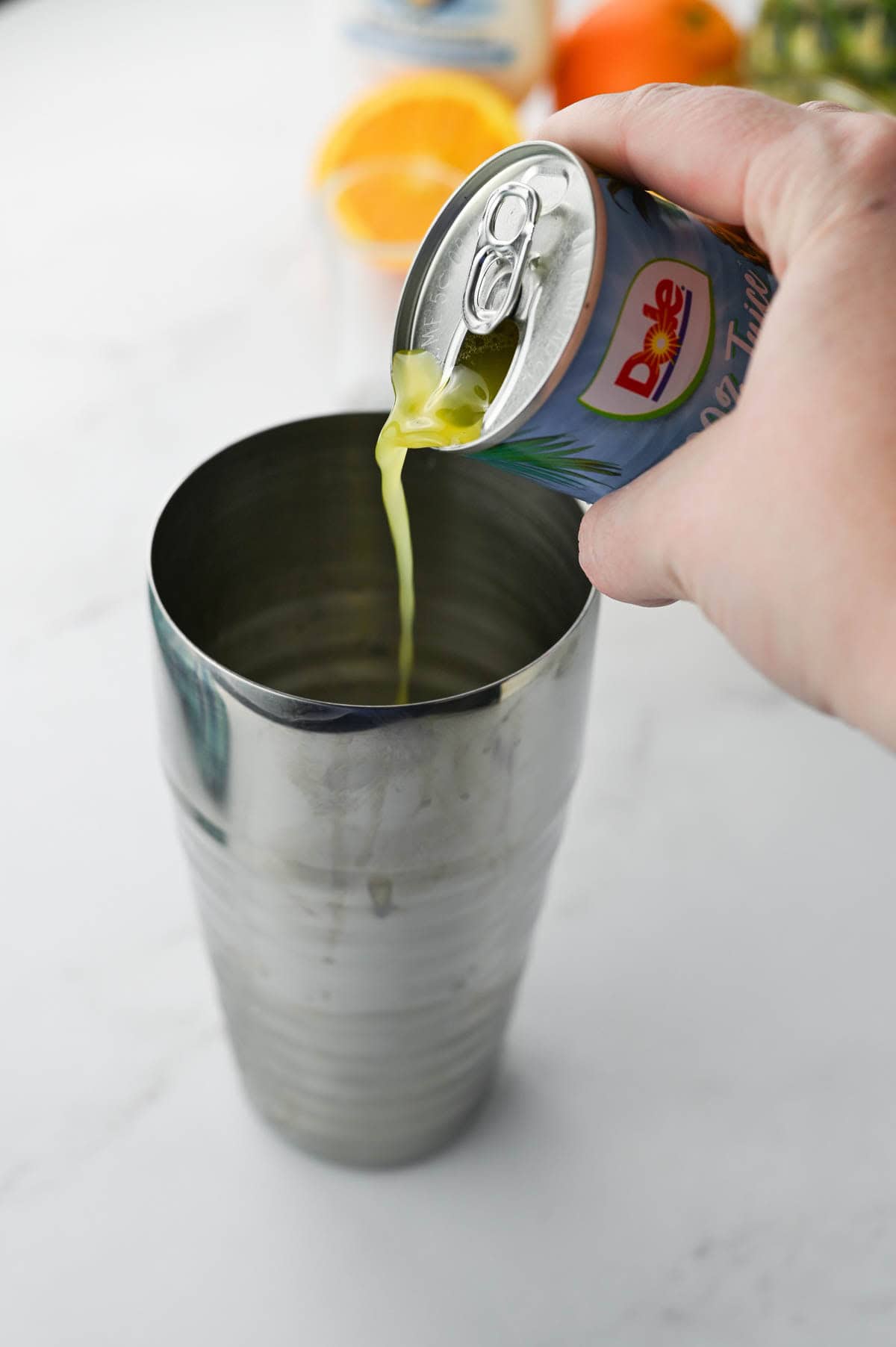 Pouring pineapple juice into a cocktail shaker.