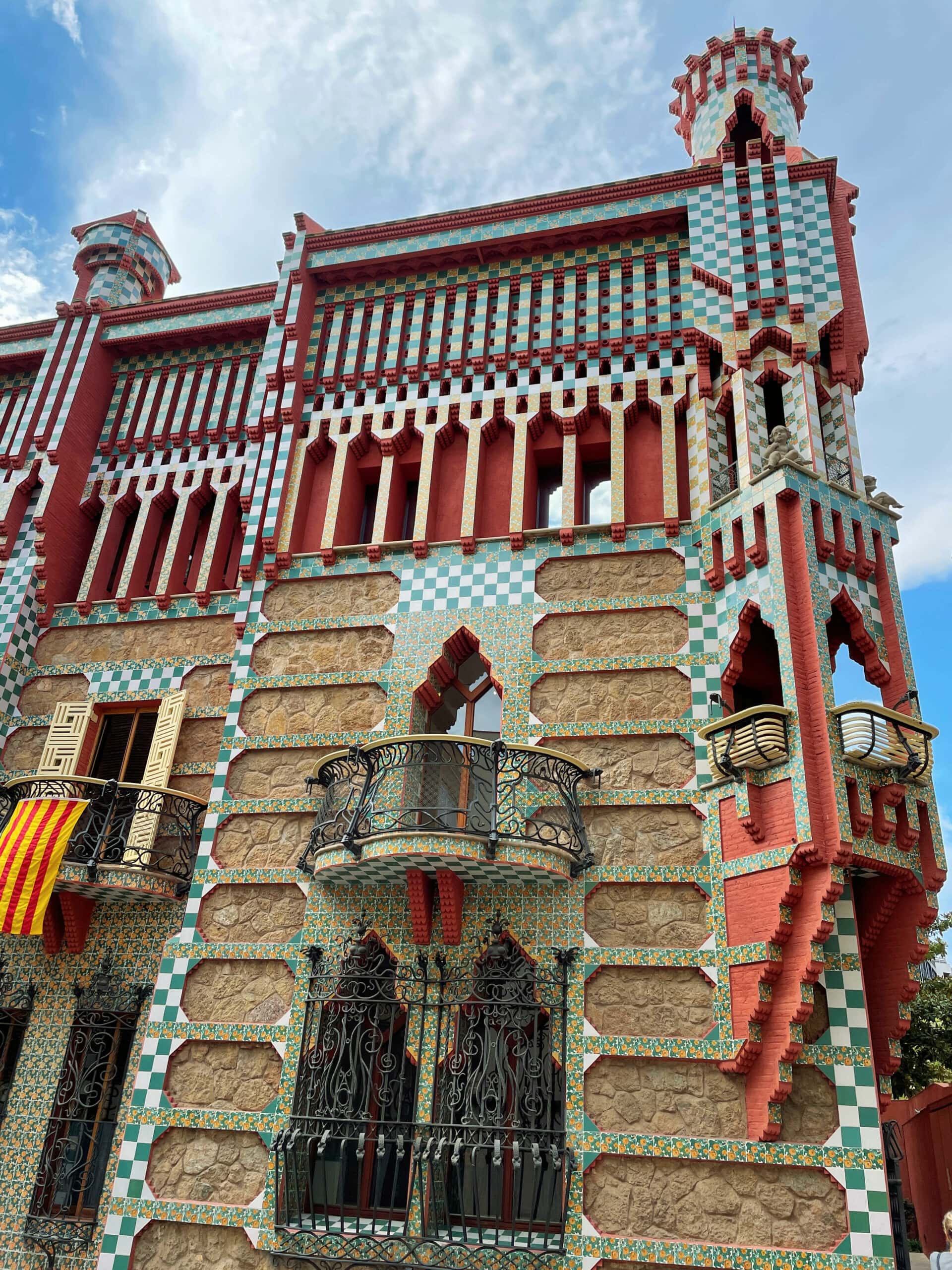 Ornamental architecture building with balcony, with green, yellow, and red stone and tile in Barcelona Spain.