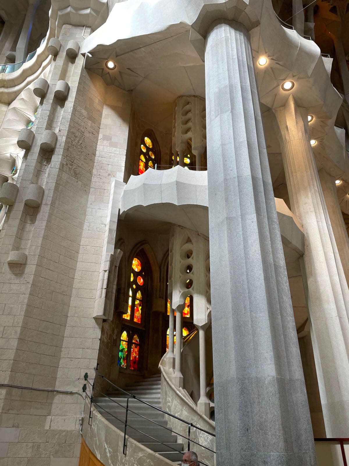 Stone spiral staircase inside a church with stained glass windows.