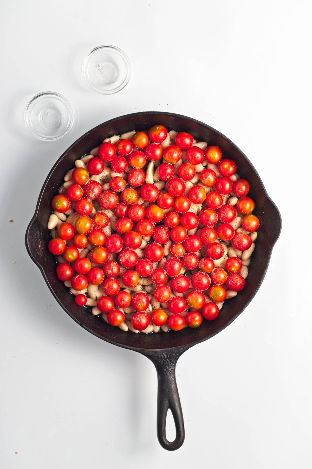 Tomatoes with beans, garlic, and oil in a cast iron skillet.