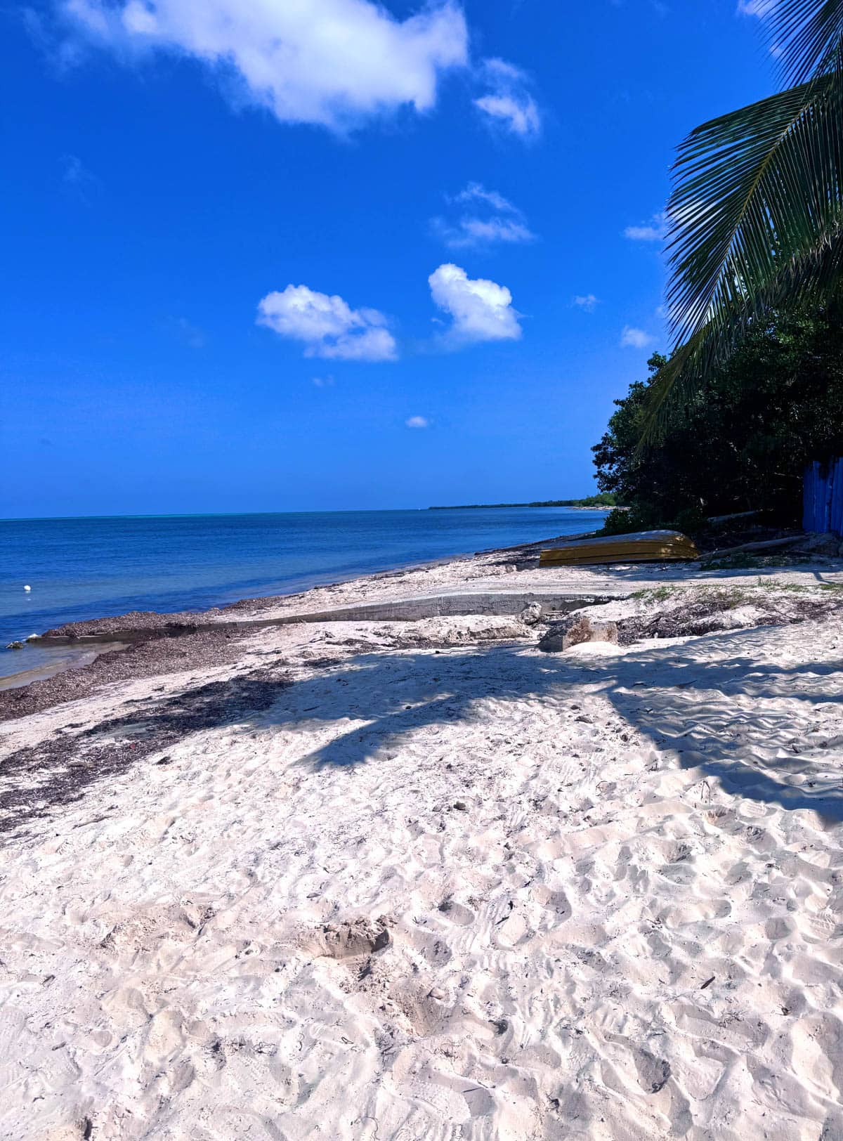 White sand beach with blue sky and a few clouds.