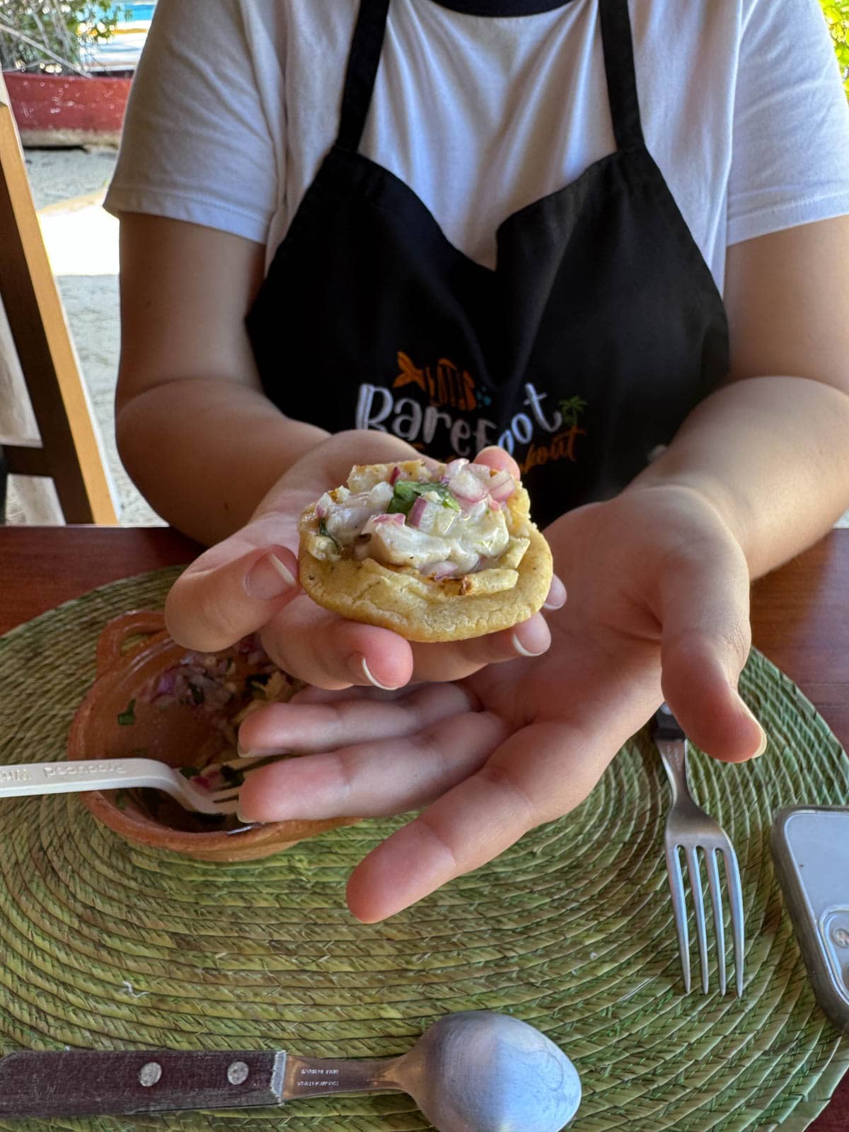 Person holding ceviche on tortilla.