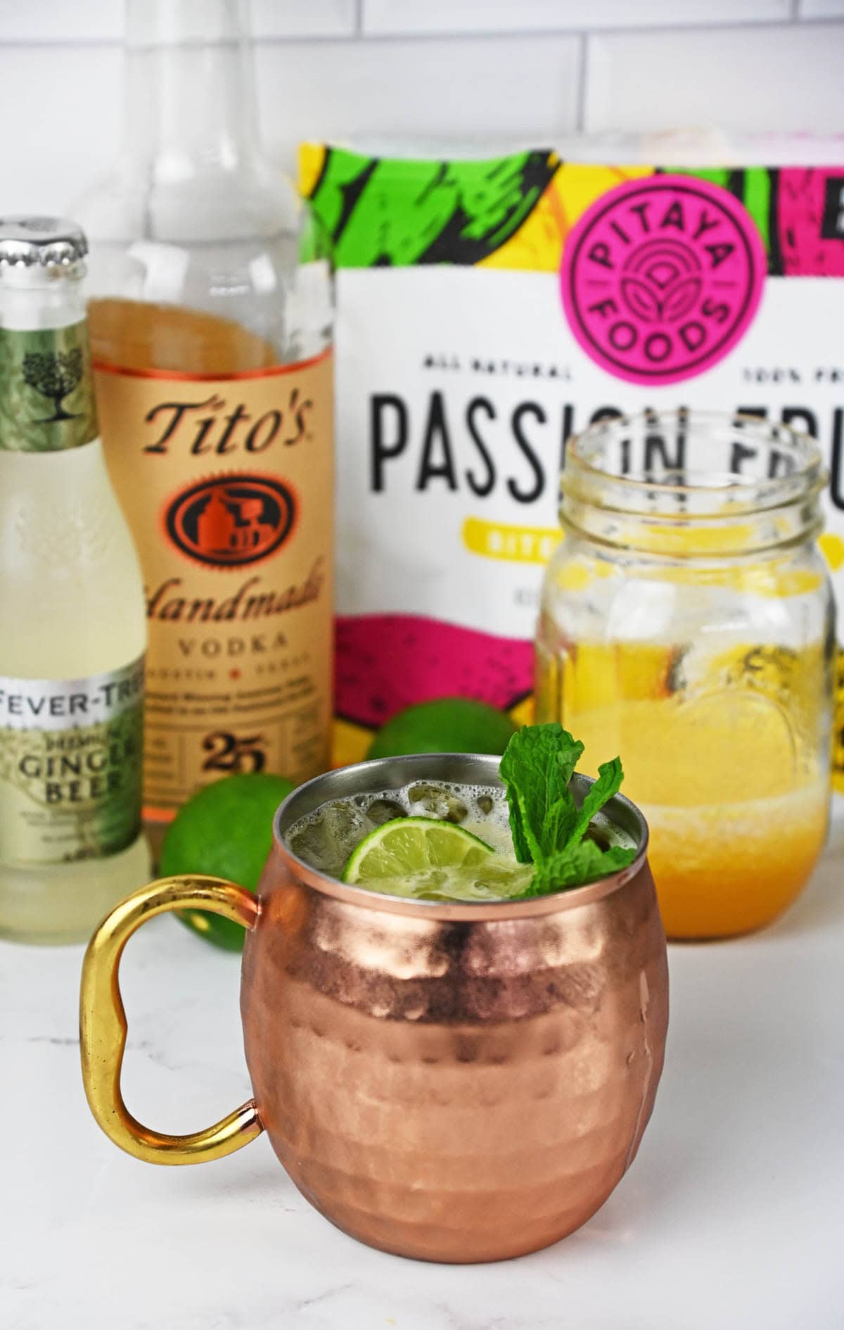 Drink with a lime and mint in a mule copper cup with ingredients in the background.