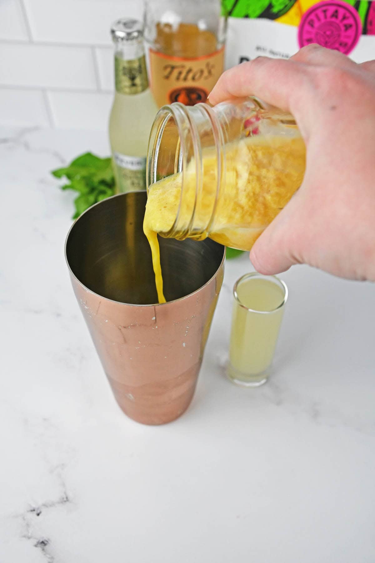 Pouring Passion fruit from a mason jar into cocktail shaker.