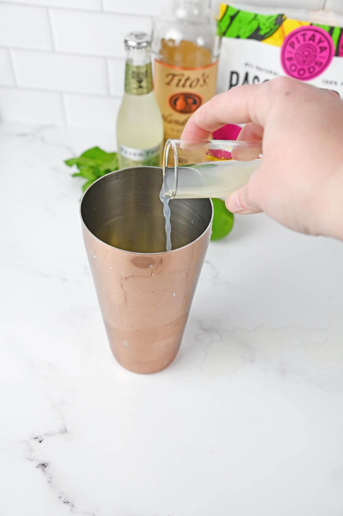 Pouring lime juice into cocktail shaker.