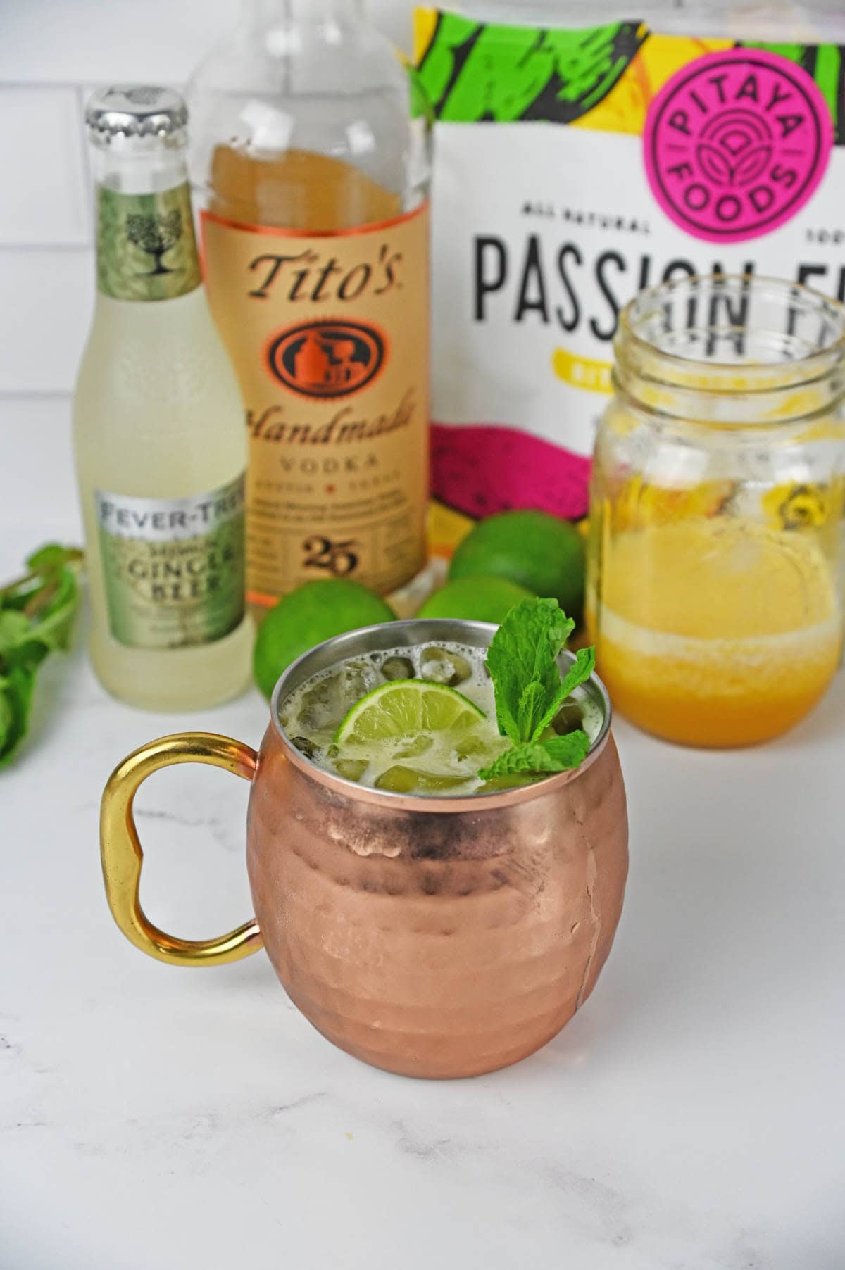 Drink with a lime and mint in a mule copper cup with ingredients in the background.