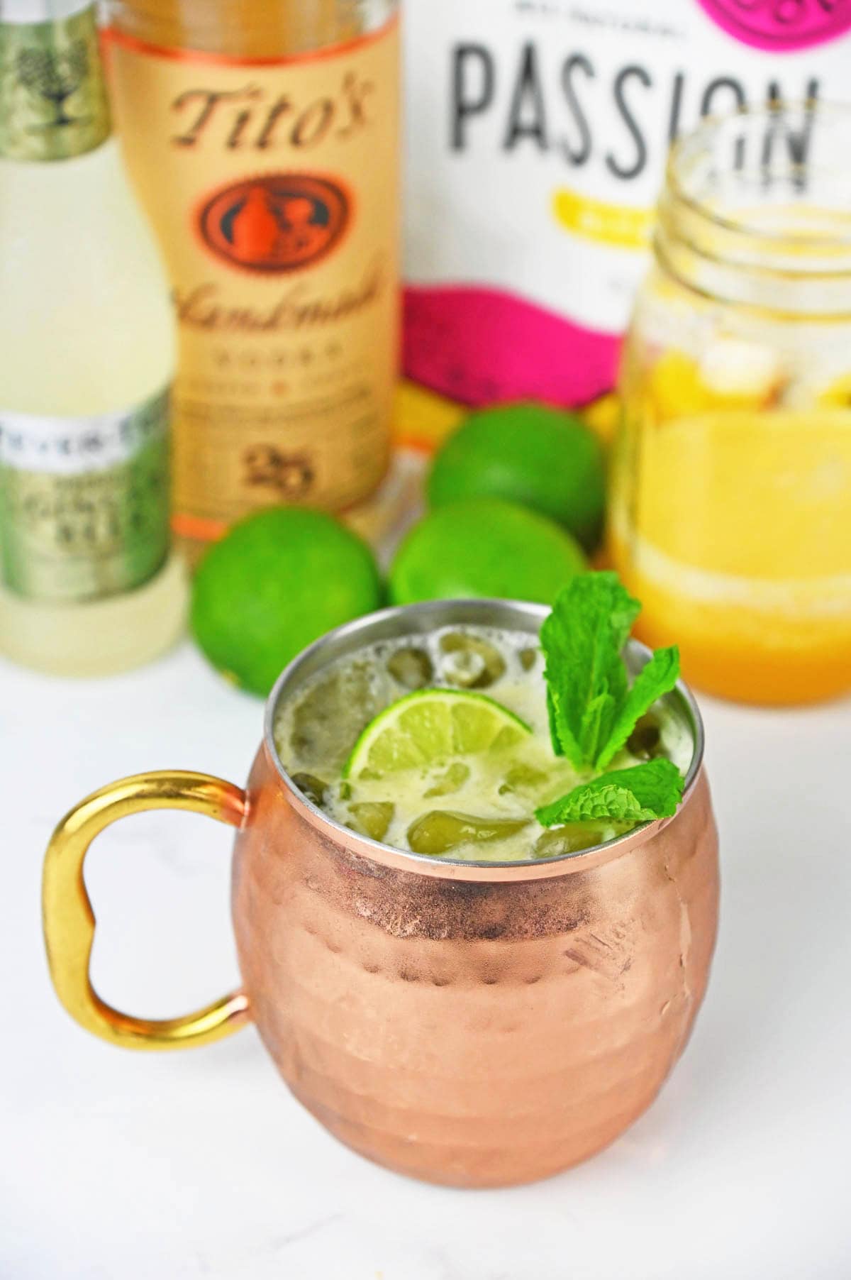 Drink with a lime and mint in a mule copper cup with ingredients in the background.