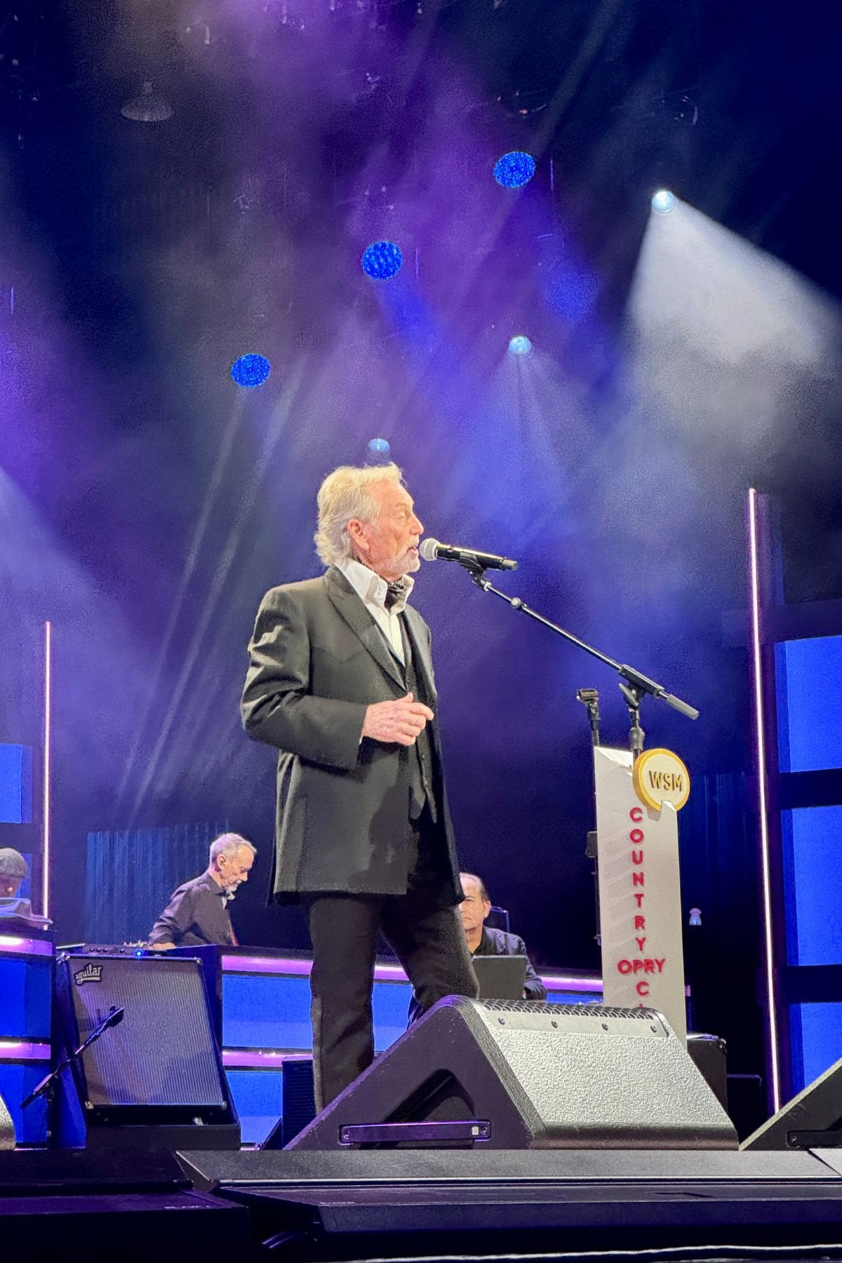 Man in a suit singing on stage.