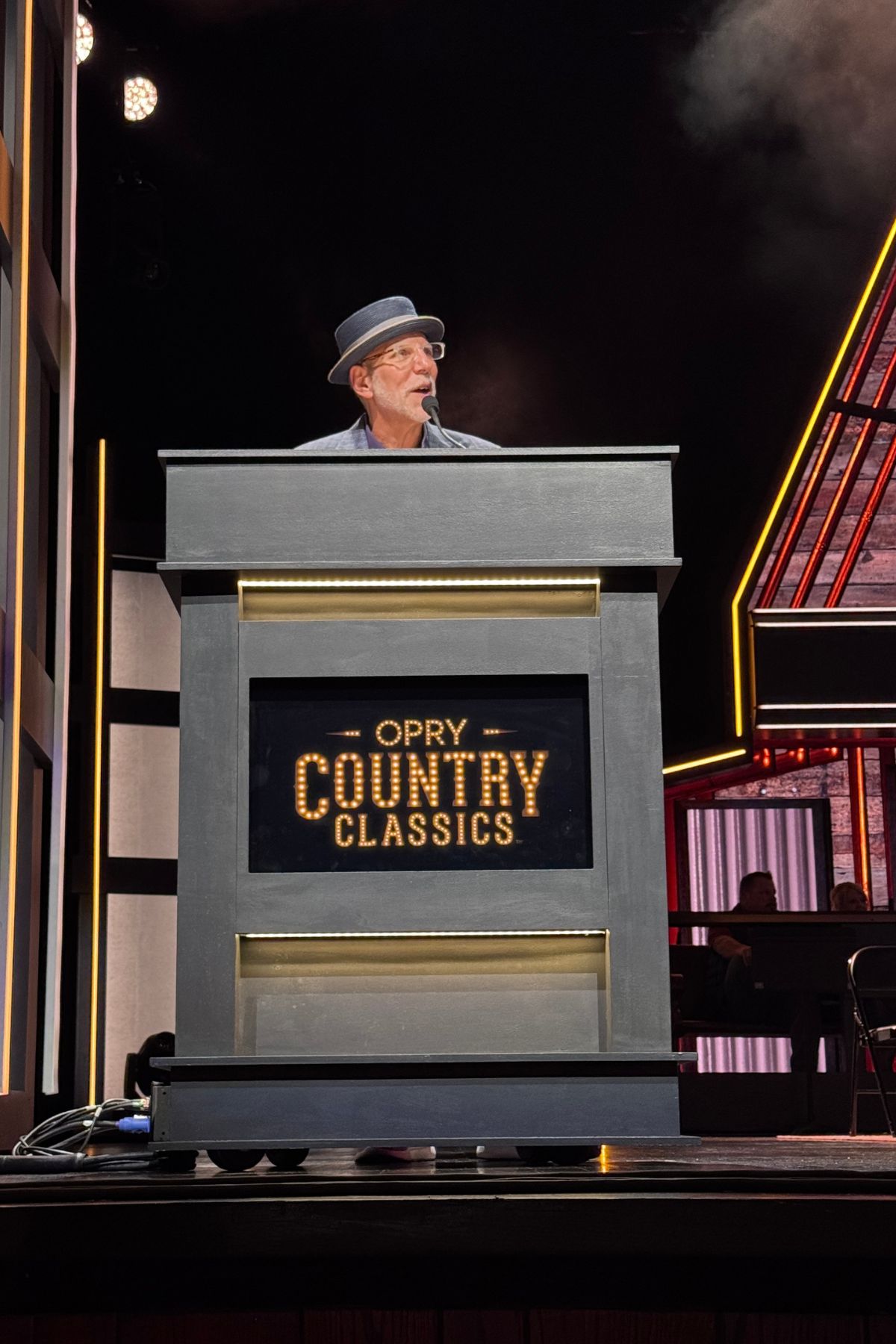 Man with gray hat at a podium on a stage.