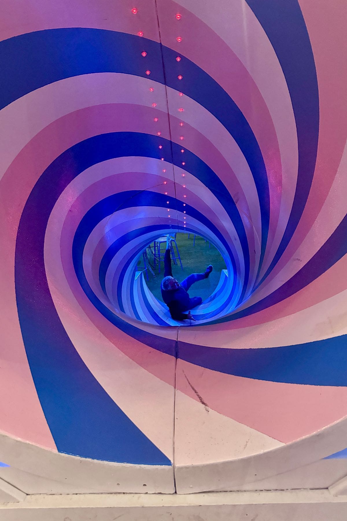 Man falling down spiral tunnel with a slide.