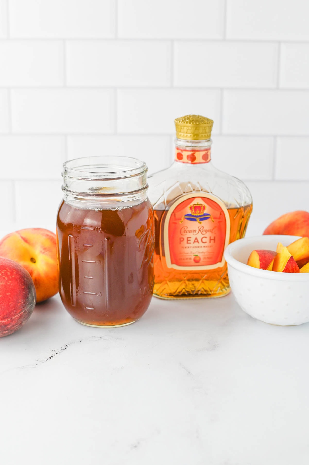 Ingredients to make a cocktail with Crown Royal and iced tea on a white counter.