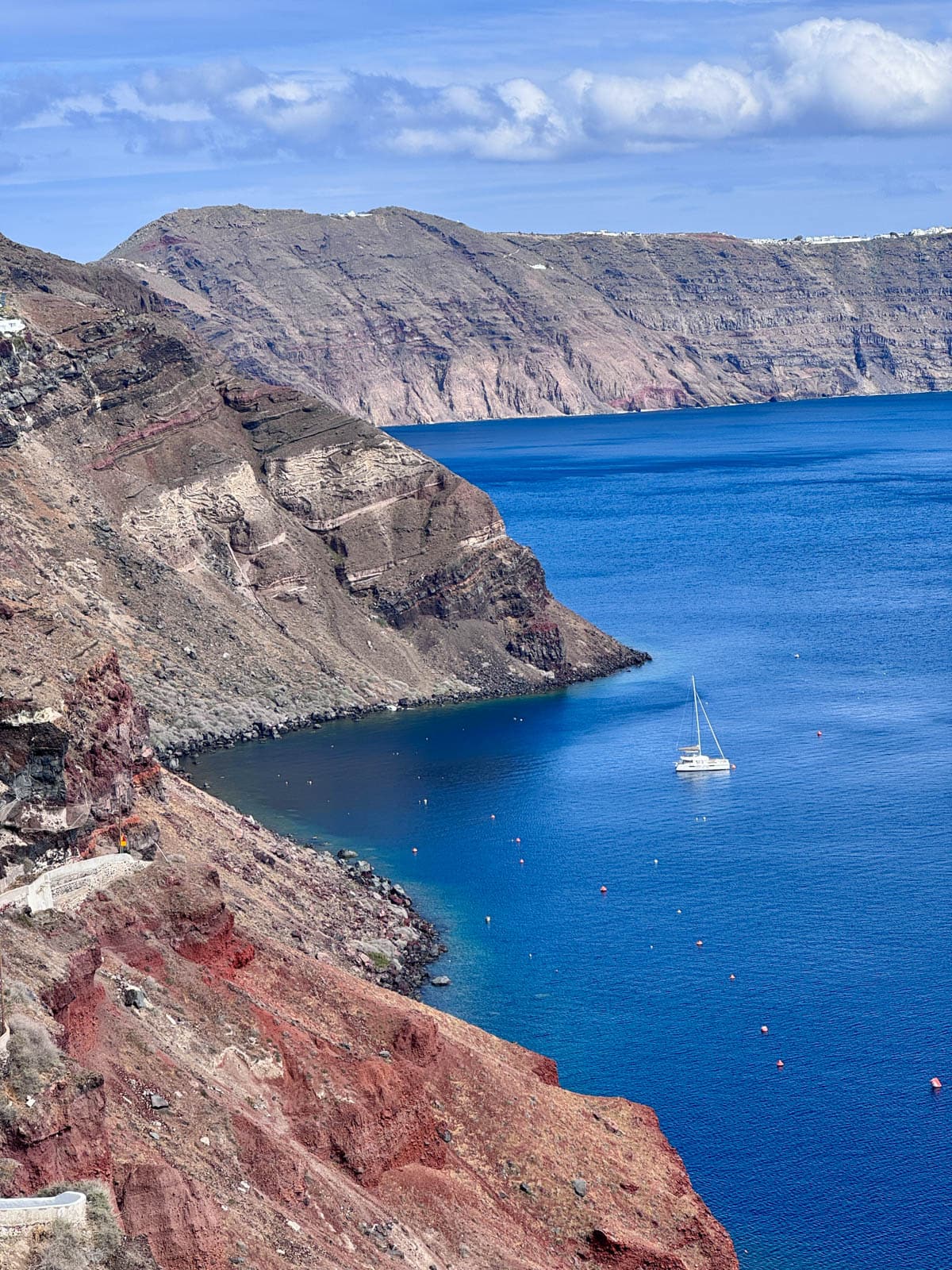 Mountains, blue sky, and blue sea with one white boat.
