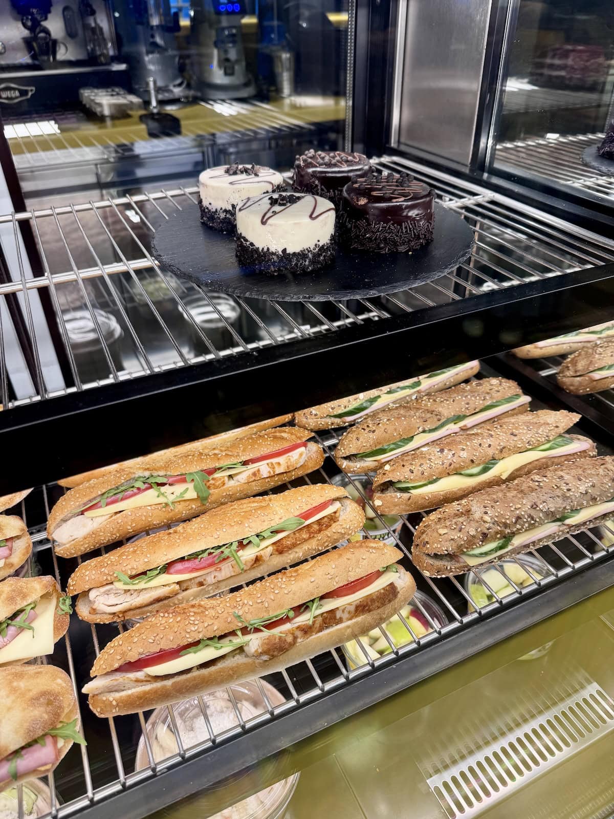 Case of sandwiches and desserts in a coffee shop.