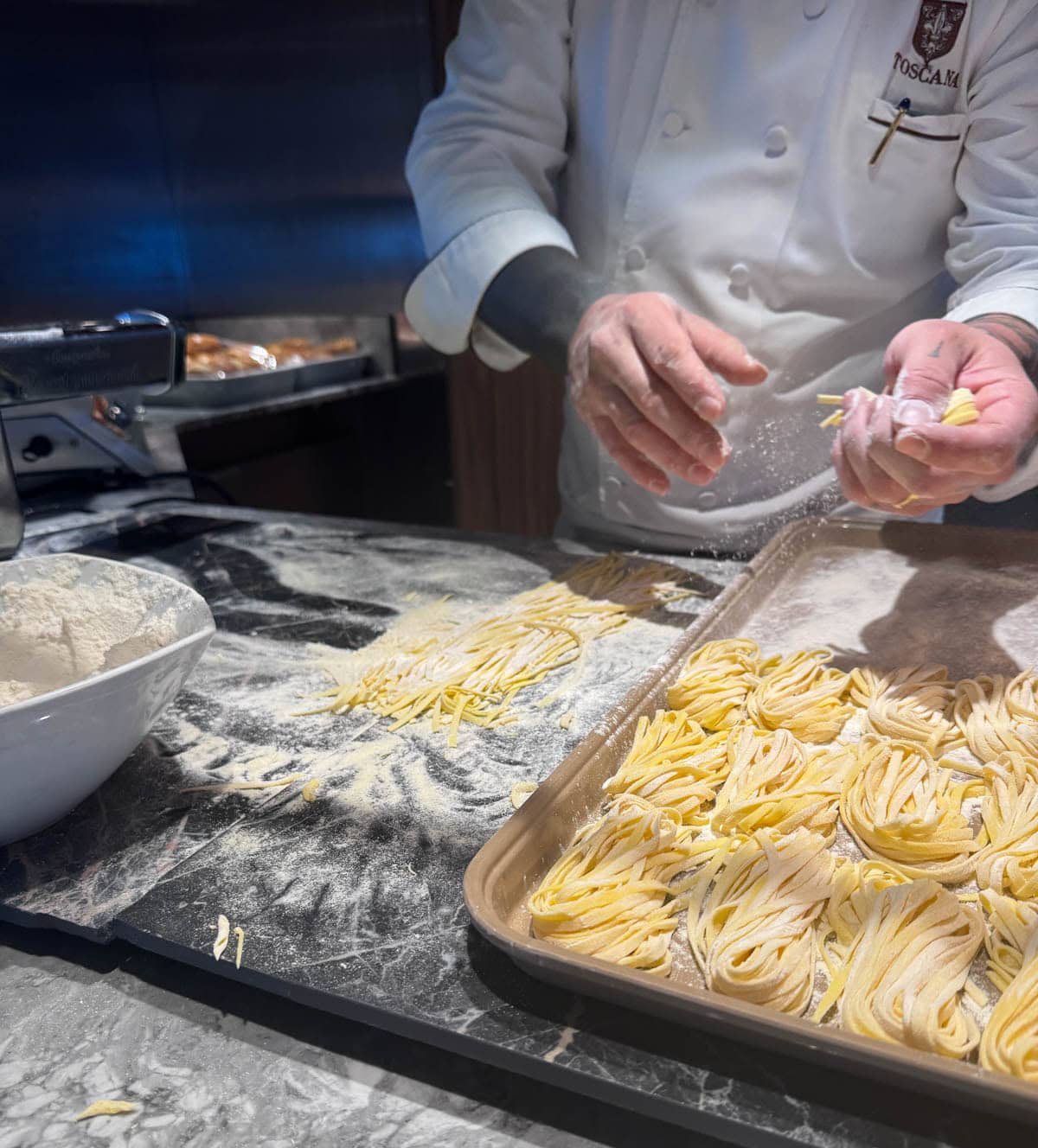 Chef making pasta and placing it on a tray in bundles.