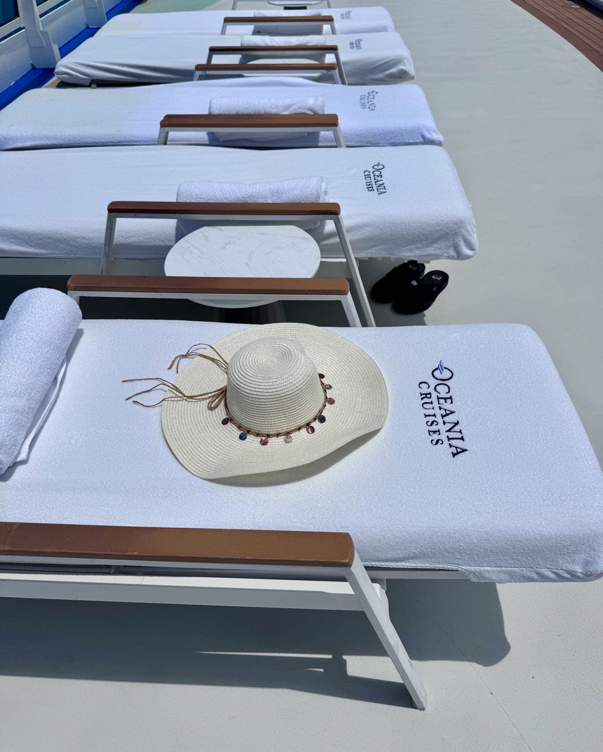 Lounge chairs on the Oceania Vista with floppy hat on the first one.