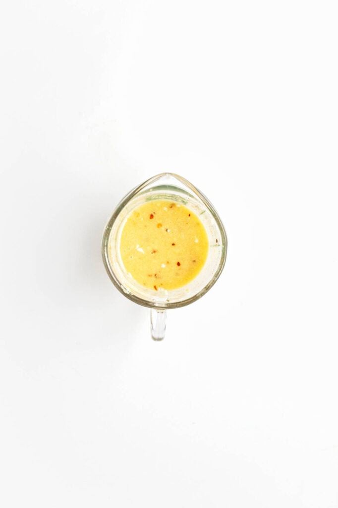Glass measuring cup full of dressing.