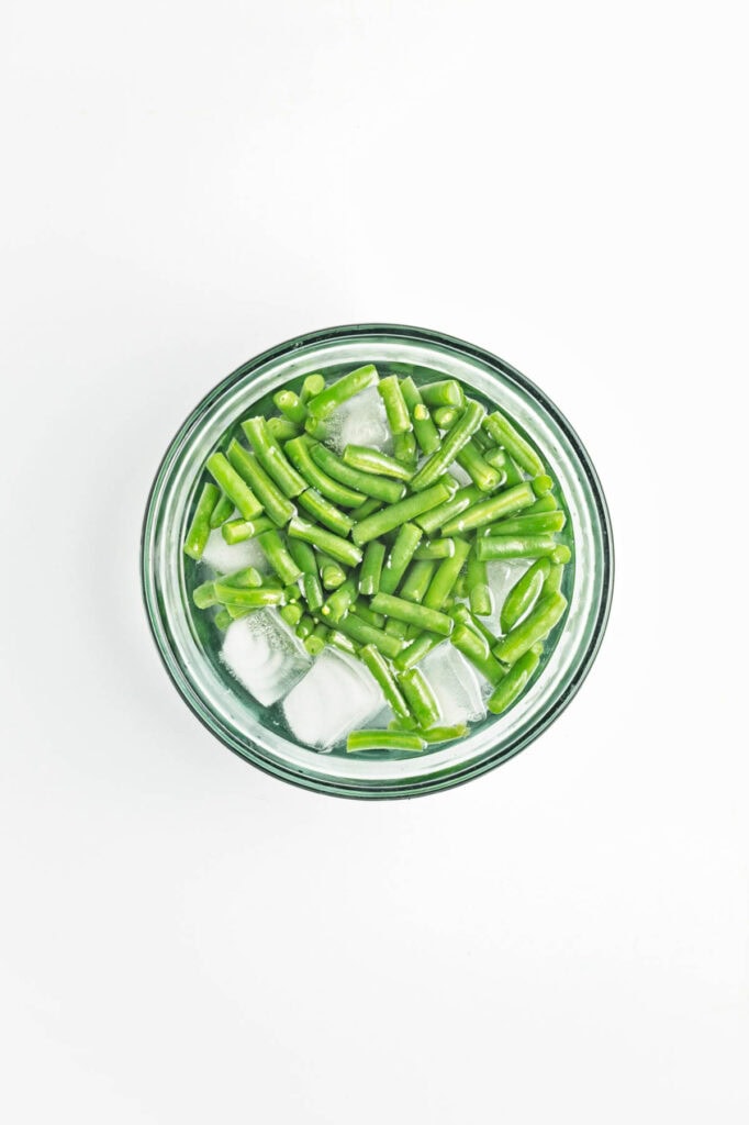 Green beans in bowl of ice water.